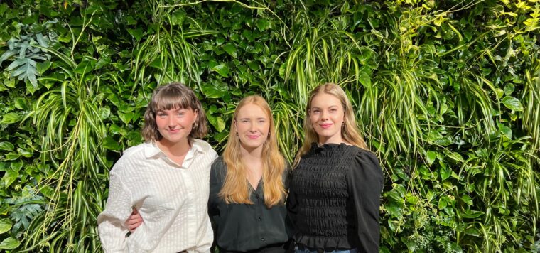 Pim, Tessa och Moa står framför kameran och håller om varandra mot en grön grönskande bakgrund.